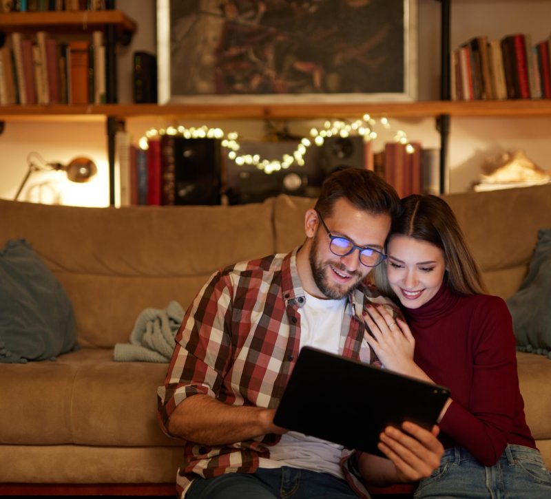 Young couple spending evening at home using digital tablet